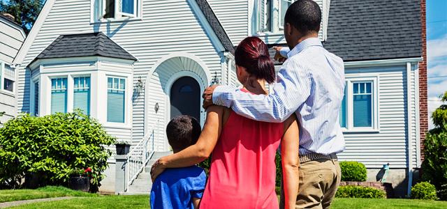 Family standing in front of a house and gazing at it